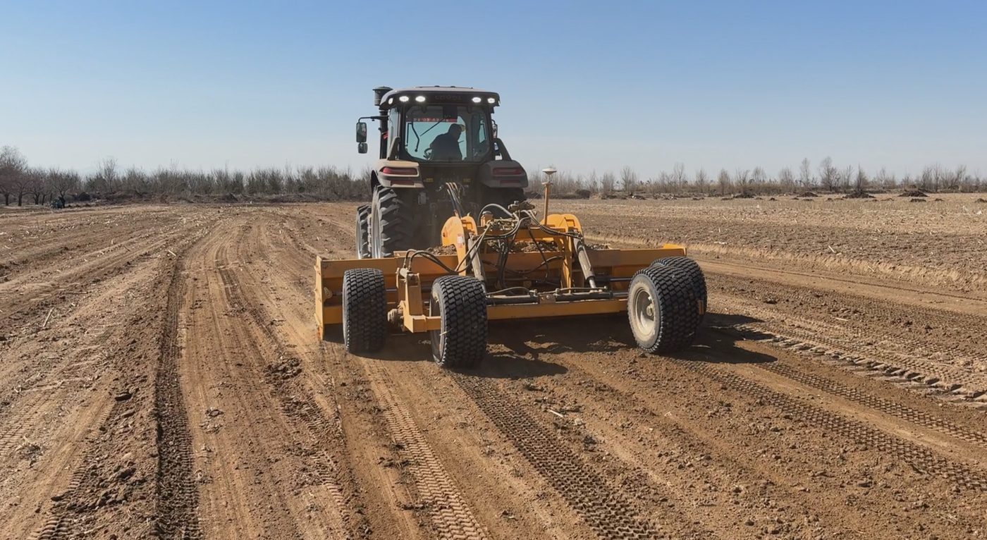 Tractor pulling land leveler across a large field